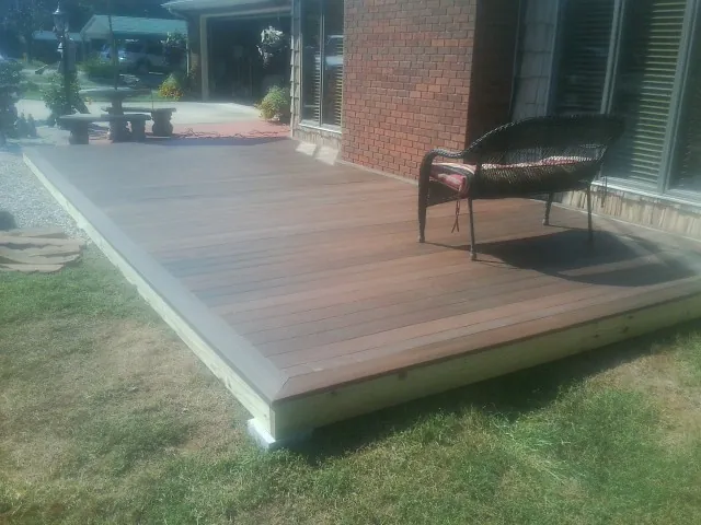 New wood deck and wicker chair beside a brick house in Midland
